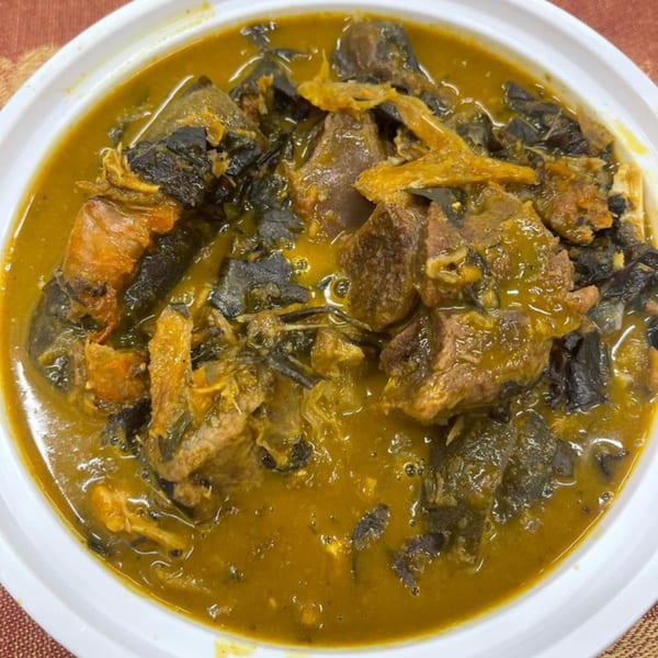 Arona Food Place's Nigerian soup with meat, fish, and dark leafy greens in a white bowl.