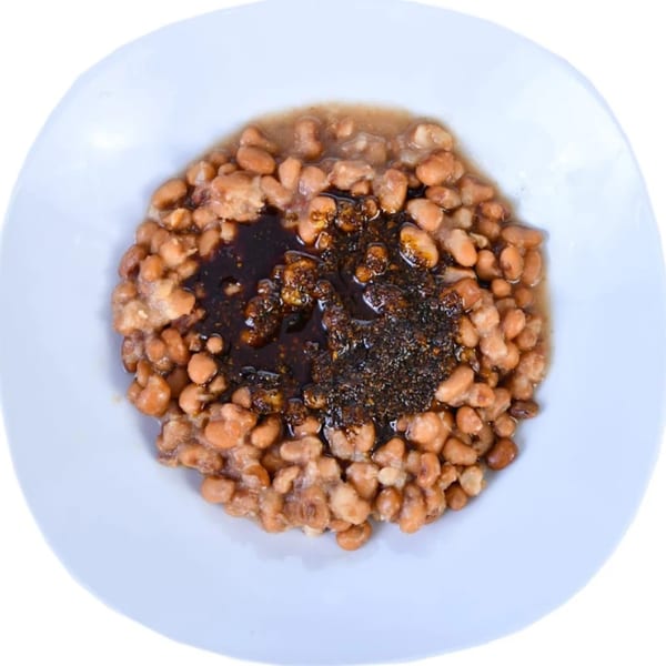 Arona Food Place's Nigerian beans porridge with dark stew, served in a white bowl.