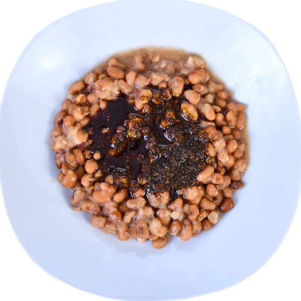 Arona Food Place's Nigerian beans porridge with dark stew, served in a white bowl.