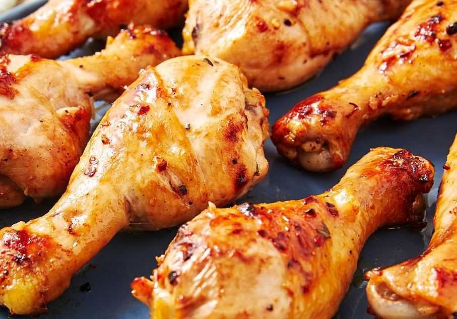 Grilled chicken drumsticks seasoned with spices and herbs on a blue serving plate.