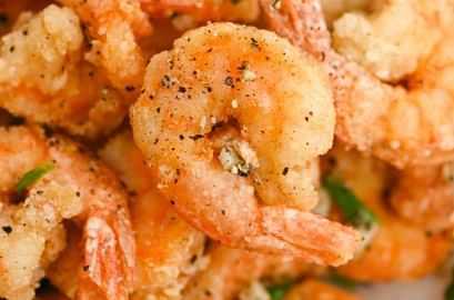 Close-up of seasoned, crispy fried shrimp with garnishing, showing texture and detail.