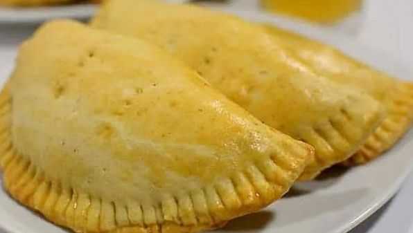 Golden-brown empanadas on a white plate, ready to be served.