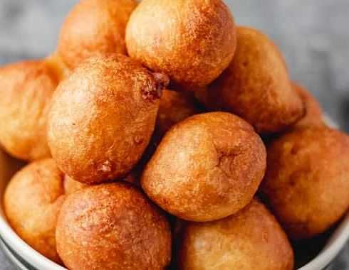 A bowl filled with golden brown, deep-fried dough balls stacked on top of each other.